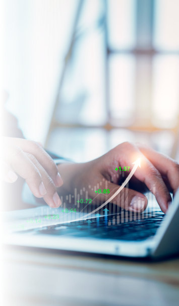 Close-up of hands typing on a laptop keyboard with a digitally overlaid rising graph and numbers, symbolizing growth or financial success. The background is blurred for emphasis on the action.